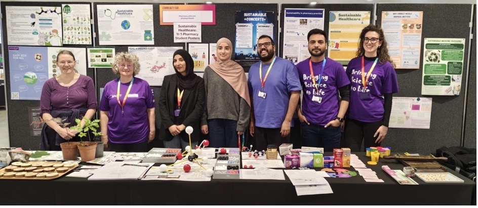 The Electro-Med Lab team at the Universally Manchester Festival, standing behind a table of demonstration materials with a Bringing Science to Life banner
